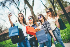 Four women with identical hair cuts and sunglasses pose for a selfie.