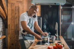 Man talking on the phone while cooking on a stove and holding a soccer ball