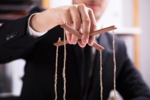 Closeup of a person's hand holding marionette strings