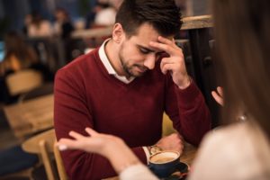 Young couple sitting in coffee shop in disagreement