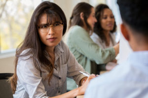 Women in classroom setting glares at person she's talking to.