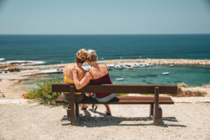 Female couple on bench admiring the sea