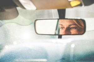 A woman's eyes reflected in her rear view mirror while driving