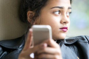 Girl grows sad after reading a message from a cyberbully.