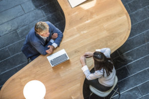 Two businesspeople sit at a curved office desk.