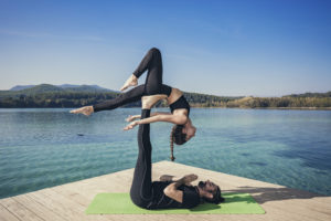 Couple practicing acroyoga in nature at beautiful lake