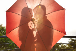 Silhouette of an affectionate couple standing behind an umbrella