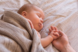 A sleeping baby rests inside a brown blanket.