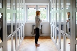 Woman standing in dressing room with mirrors on each of the locker doors