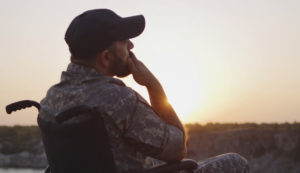 Military veteran sitting in wheelchair, thoughtfully watching a sunset