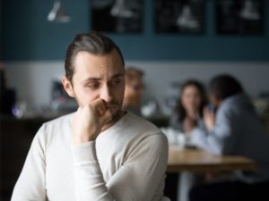 A man sulks with his back to his friends