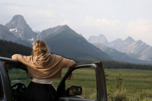 Woman looking at mountains from her car