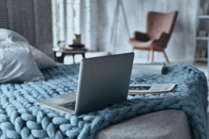 Close up of laptop and magazine on a blue quilt.