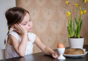 A girl looking sadly at her breakfast of a bagel and poached egg