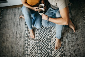 Couple sitting on the floor, drinking coffee