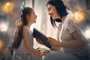 Mother and daughter reading in a blanket fort