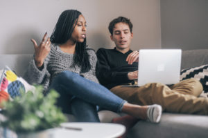 Couple doing online therapy on their couch.