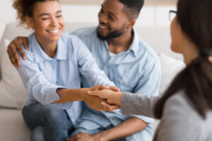 Happy couple shaking hands with therapist after a successful session.