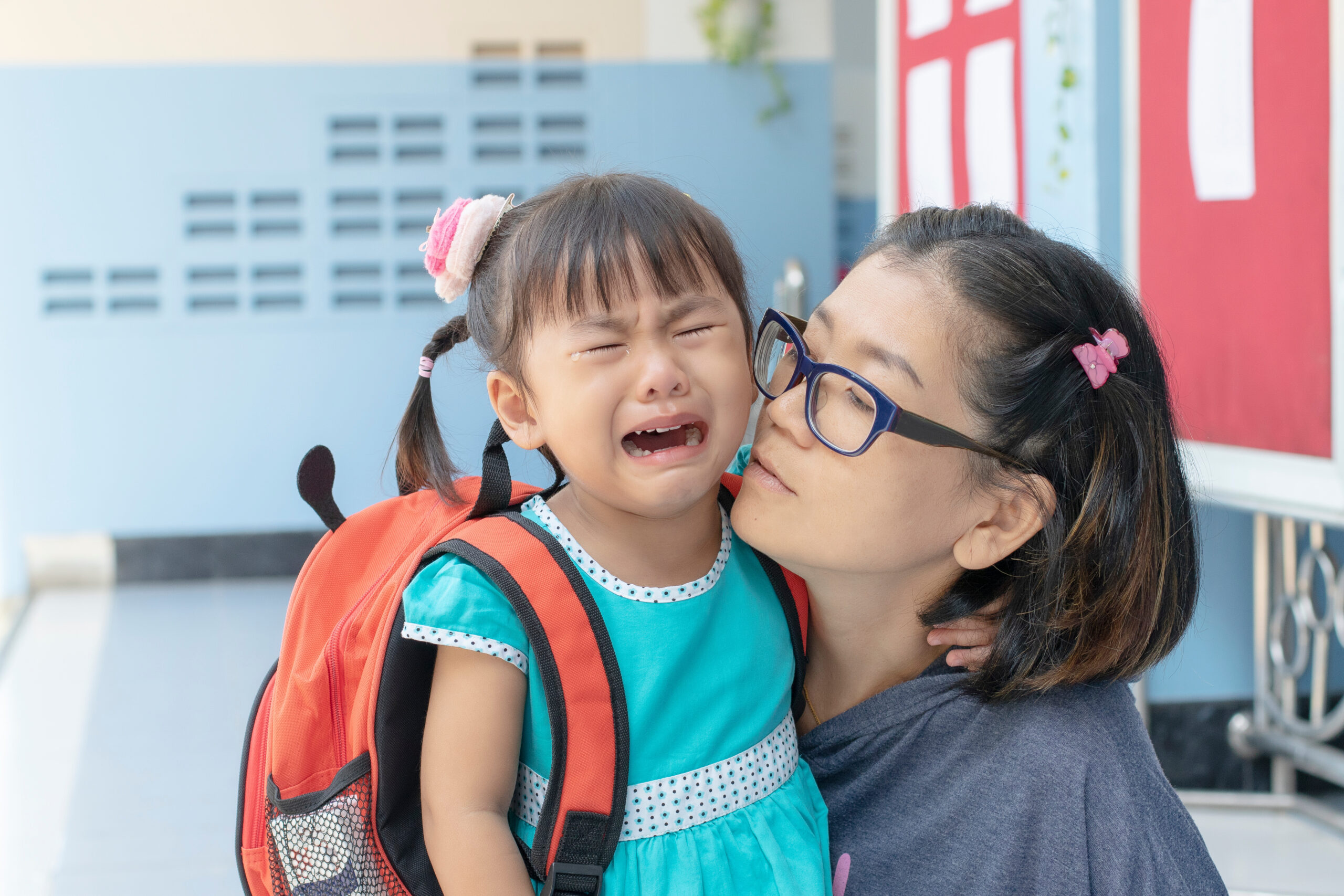 Young child crying with mom at school drop-off