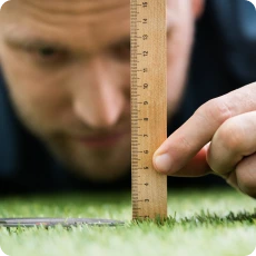 Man measuring grass up close, illustrating Perfectionism and Childhood Trauma.