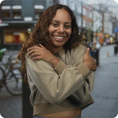 woman smiling and giving herself a hug to promote self-kindness and emotional well-being