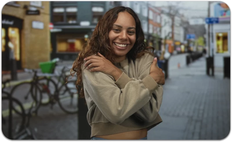 woman smiling and embracing herself to show self-kindness and emotional well-being