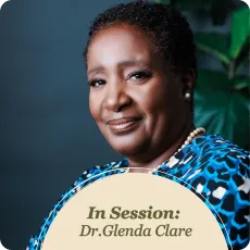 Professional portrait of Dr. Glenda Clare smiling, wearing a blue top and pearls, ready for a session.