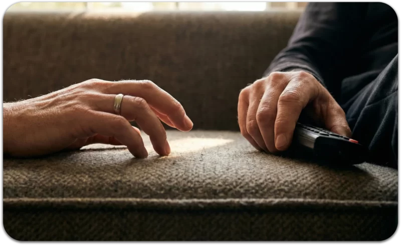 Two hands rest on a couch with space between them, symbolizing emotional distance and feeling lonely in a relationship.