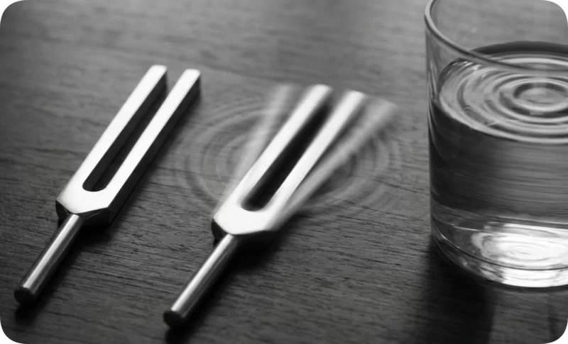 Self-Doubt in Relationships: 5 Ways to Rebuild Self-Trust 3 Vibrating tuning fork makes ripples in water and a glass, symbolizing how self-doubt affects relationships.