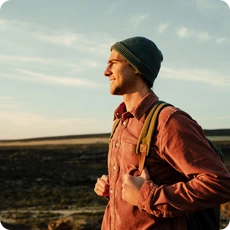 A young man with a backpack smiling outdoors, symbolizing finding closure and moving forward with hope