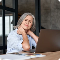 Woman with neck pain at a laptop for a chronic pain cycle article