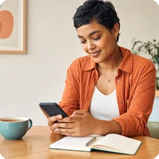 Person using mood tracking app beside a journal