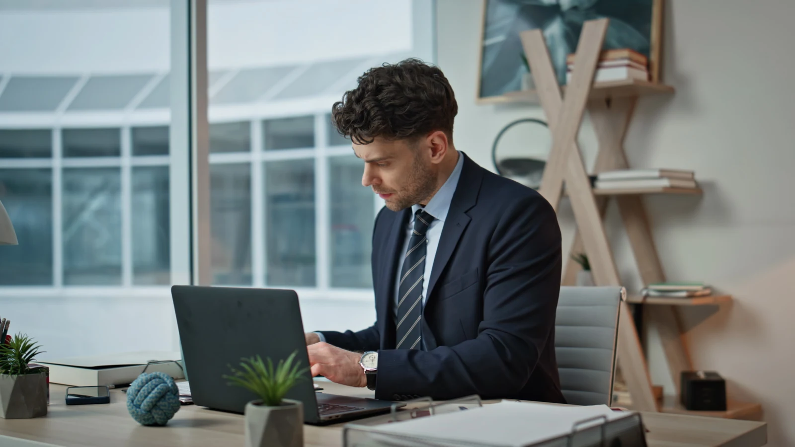 High-achieving professional working at a laptop and reflecting on success and fulfillment