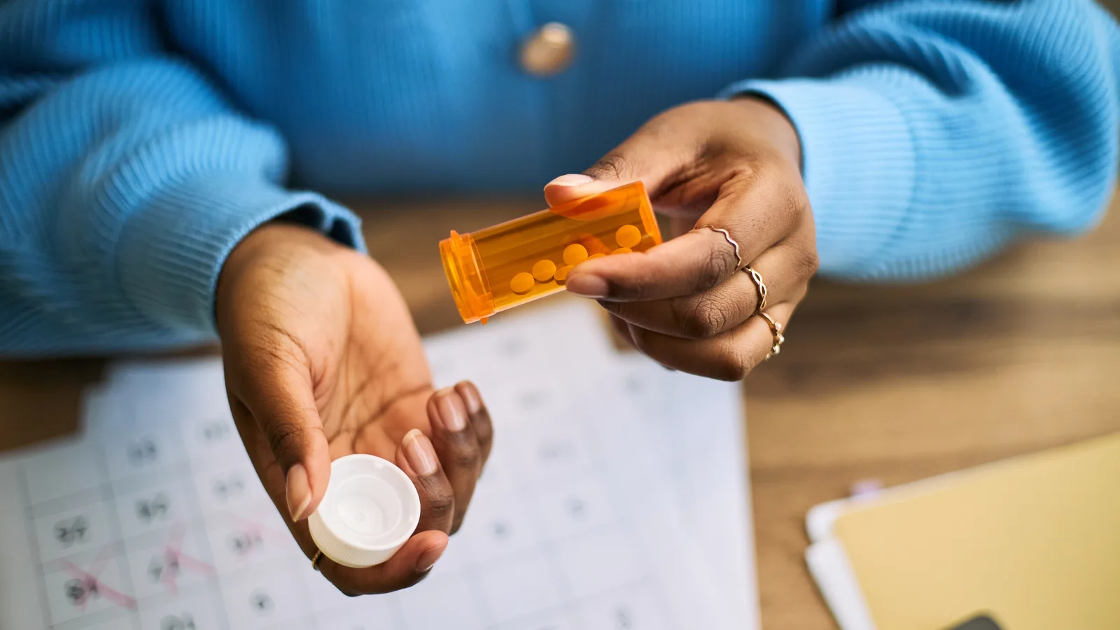 Black woman managing medication with a calendar, representing chronic illness mental health