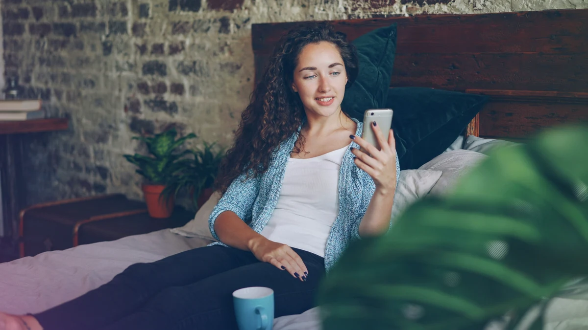 Person using a smartphone at home, representing cycle awareness and emotional self-care