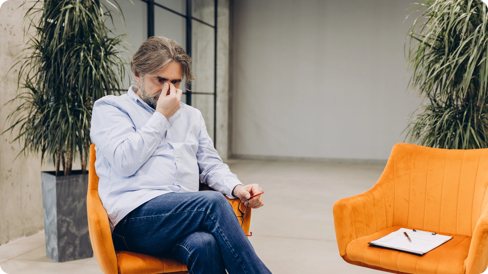 Therapist Burnout: Do You Need Rest, Support, or Redesign? 1 Person sitting in a therapy office chair and rubbing his eyes from stress