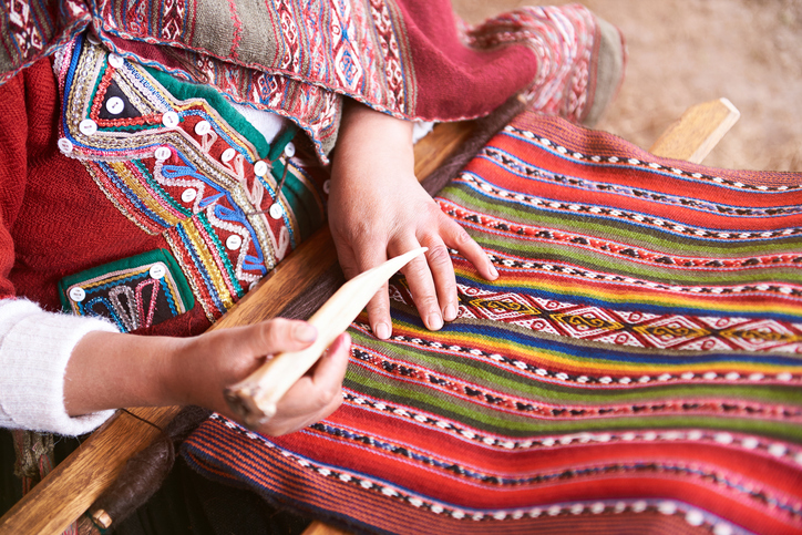 Woman sitting and weaving colorful tapestry