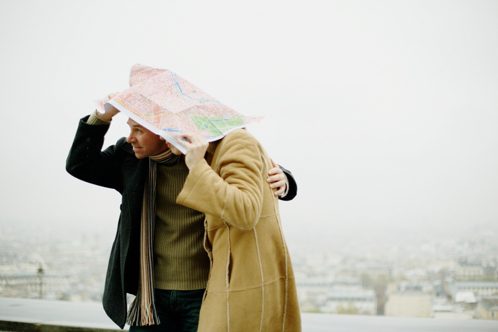 Couple taking shelter from rain under map