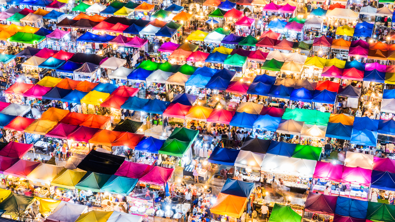 Bird's eye view of a bustling marketplace with colorful tents at night