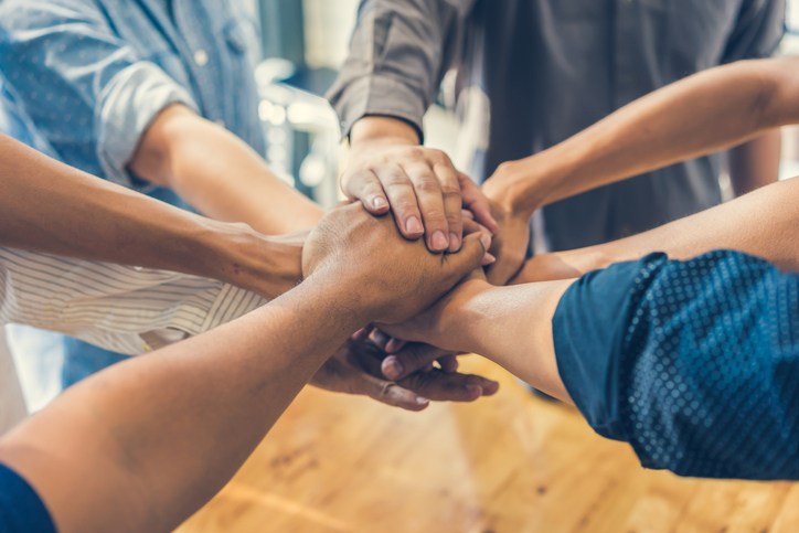 Group putting their hands together in teamwork pose