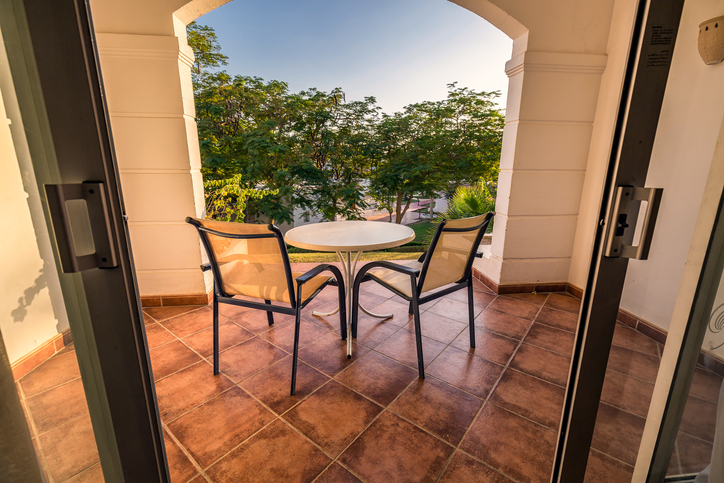 Two chairs and a table on a porch, overlooking tropical greenery