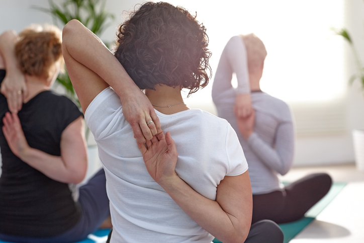 Woman stretching arms behind back in yoga class