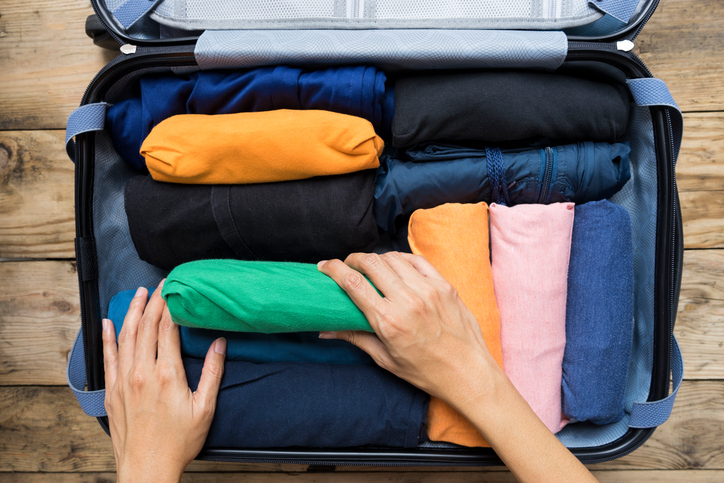 Overhead view of hands packing suitcase