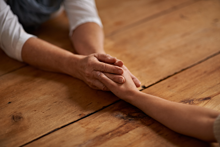 Mother holding daughter's hand supportively