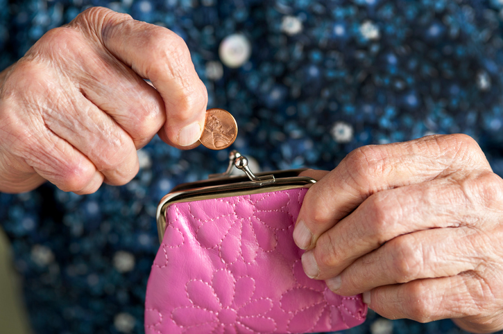 Wrinkled hands take a penny from a purse.