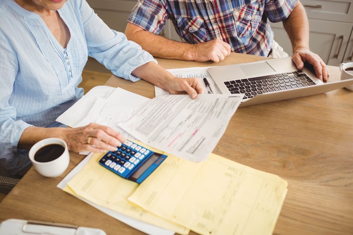 A senior couple checks their bills while drinking coffee.