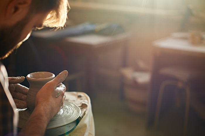 Man spinning clay pottery on wheel