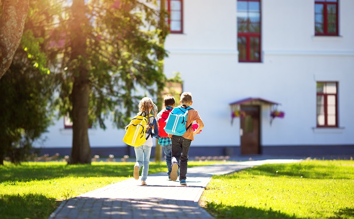 Three children walking to school on a sunny day