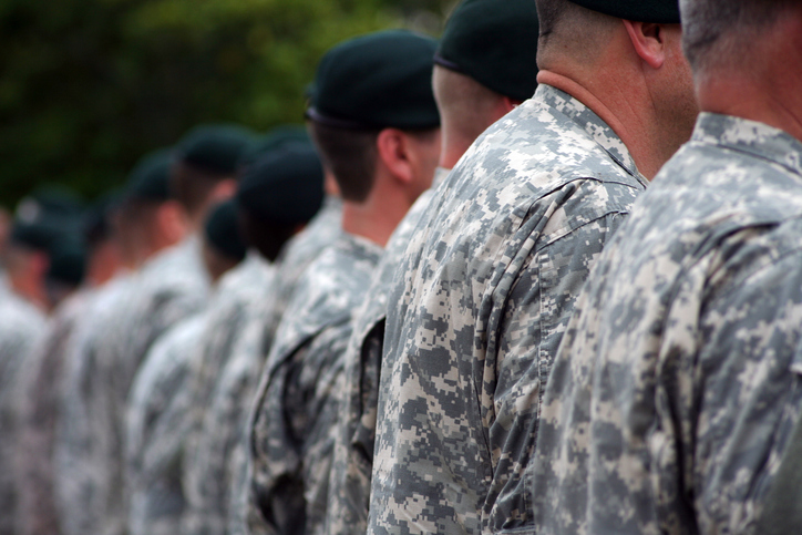 A line of veterans in uniform faces away from the camera.