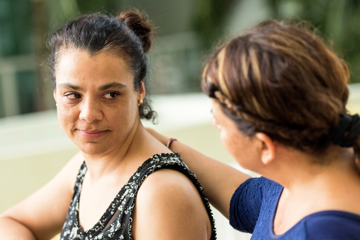 A woman comforts a friend who seems to have been crying.